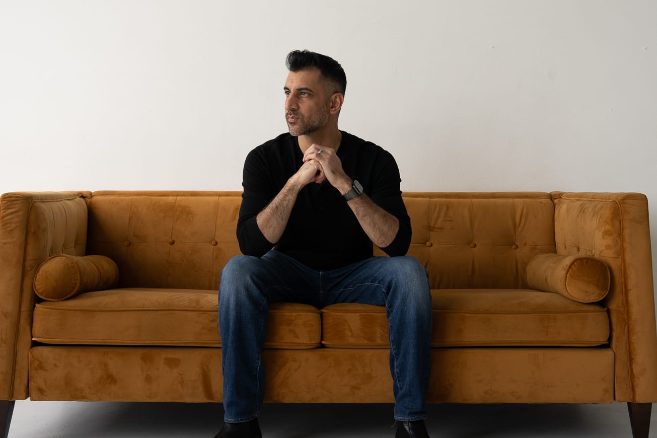 Aashay seated on a wide ochre sofa.