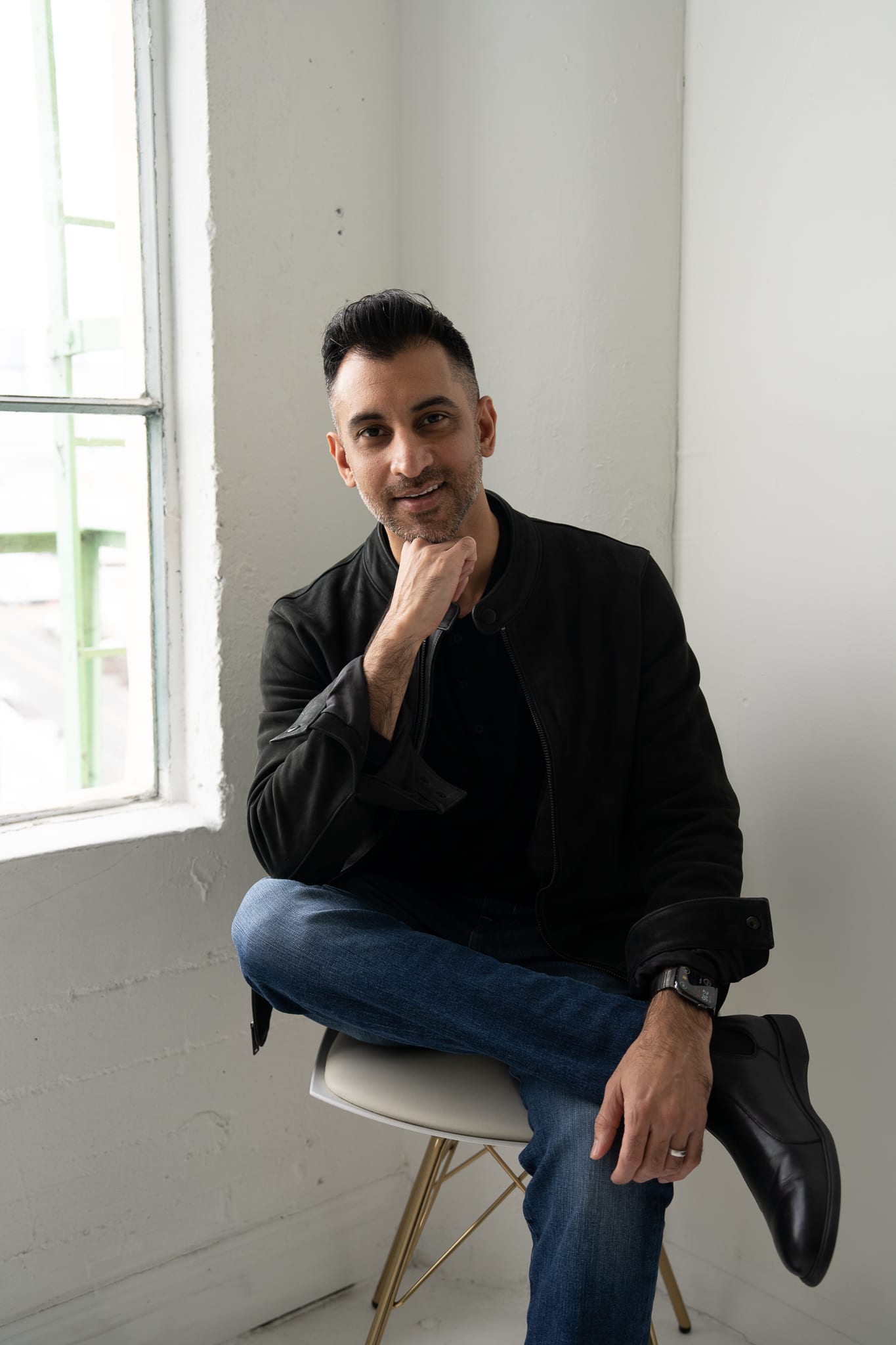 Aashay seated on a white Eames chair, slight smile.